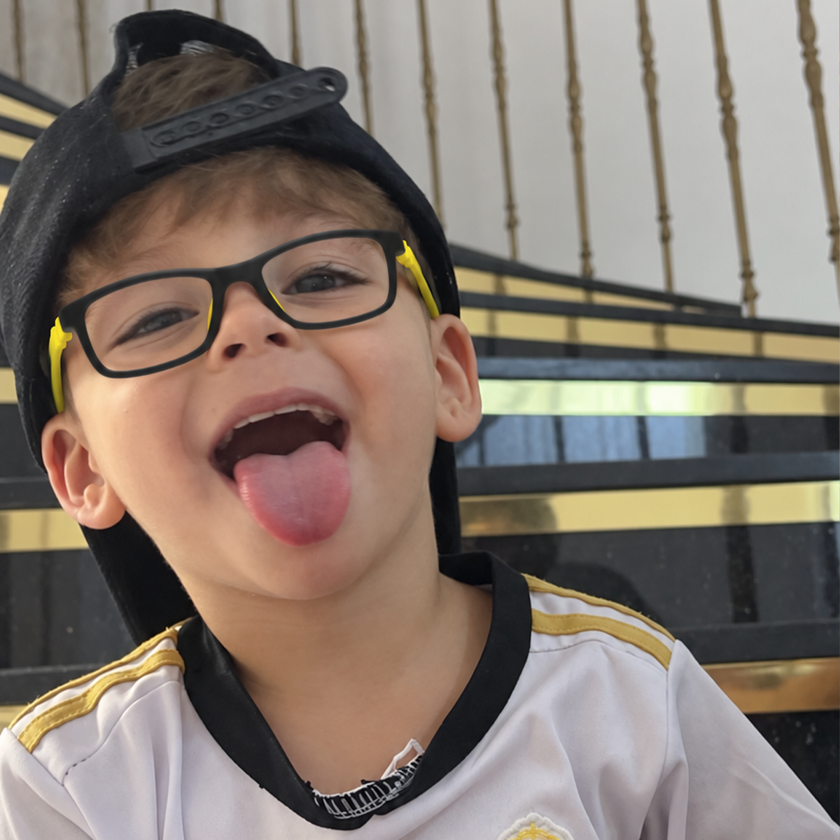Child wearing Bailey eyeglasses with black frames and yellow accents