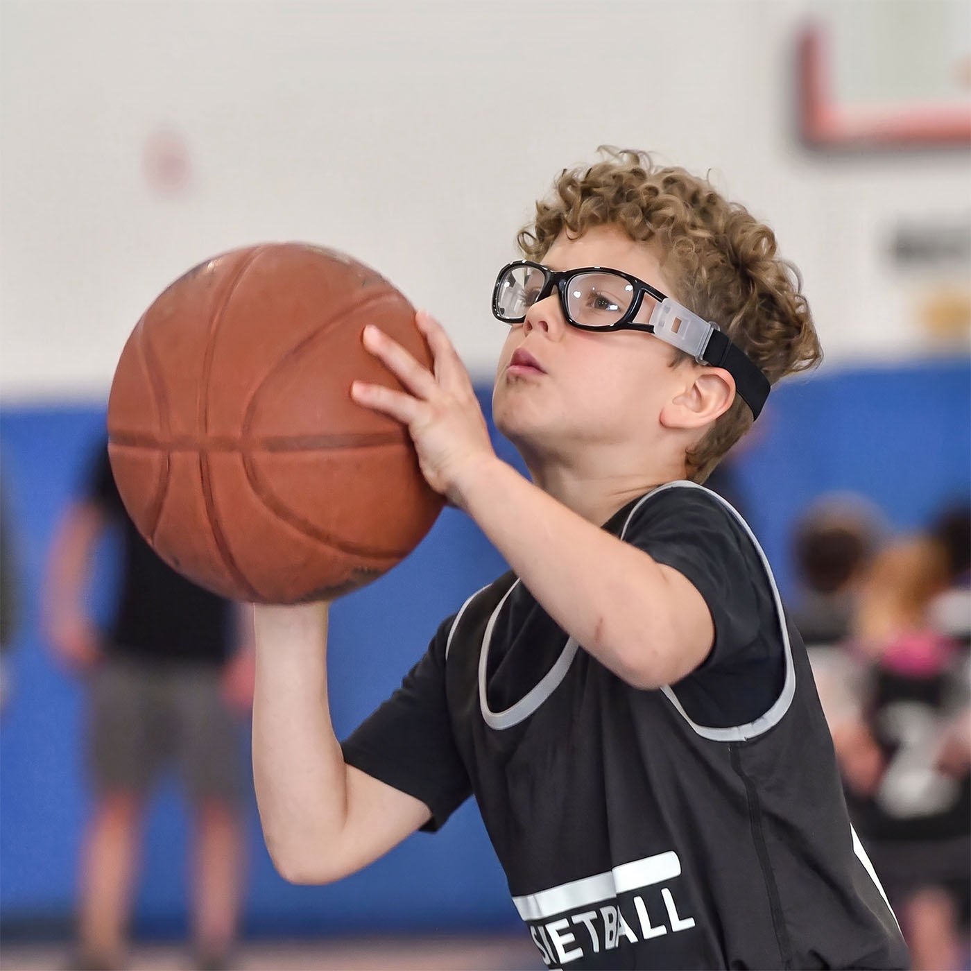 Child wearing black safety goggles with white adjustable side pieces
