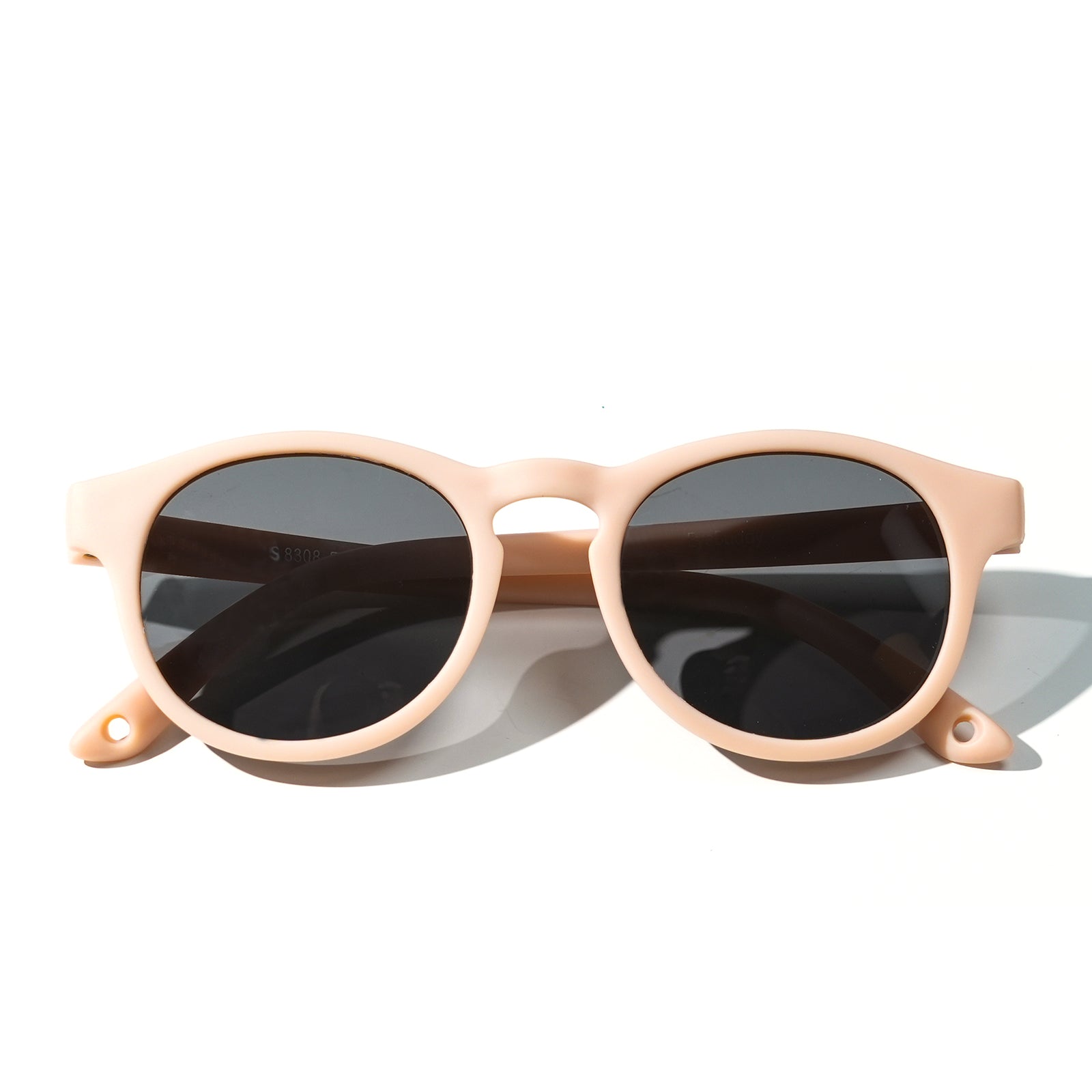 Sunglasses with light blush frames and dark tinted round lenses