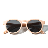 Sunglasses with light blush frames and dark tinted round lenses