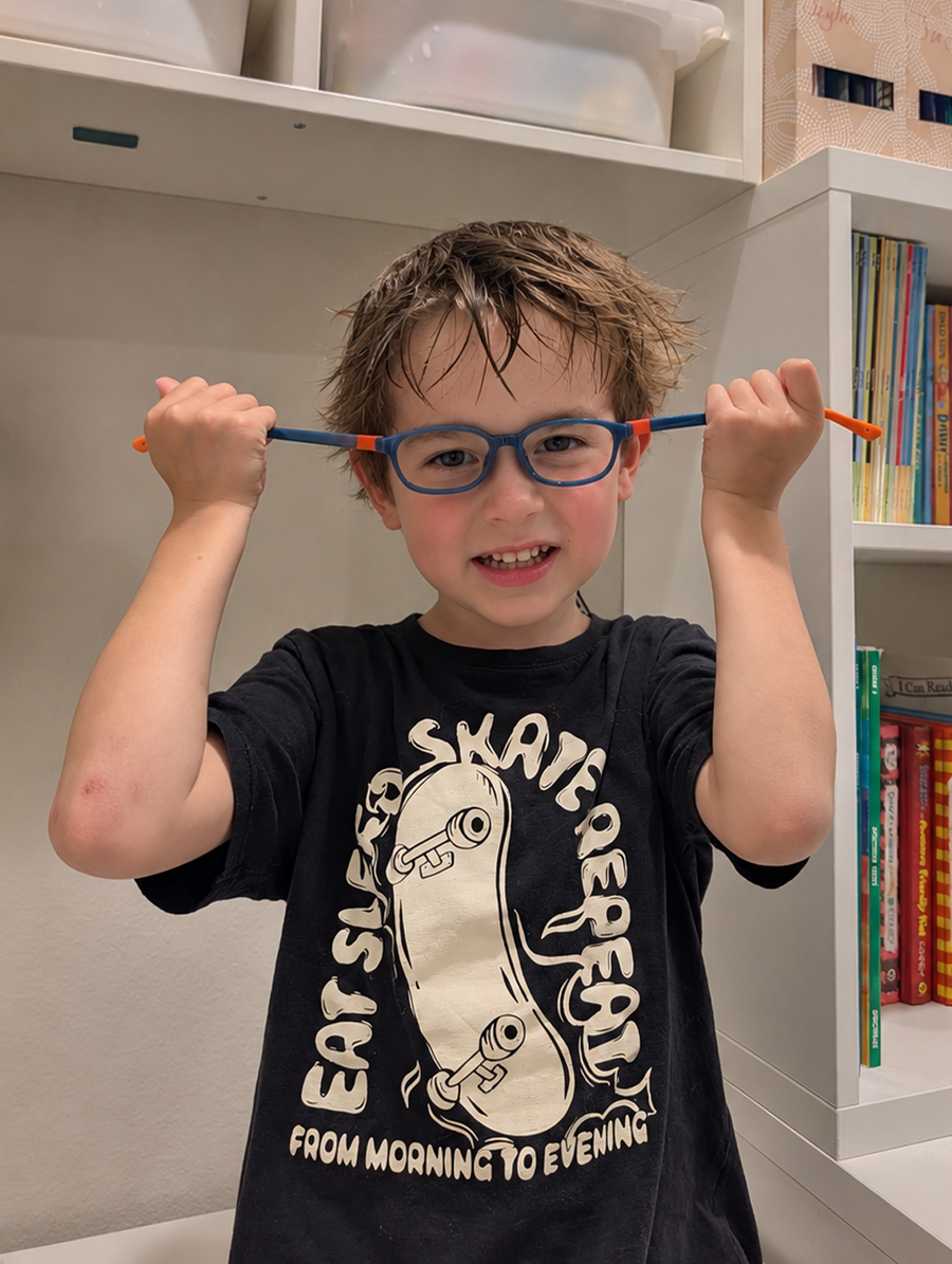 Child wearing blue and orange flexible EyeBuddy glasses