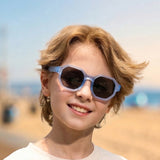 Child wearing sunglasses with a beach background
