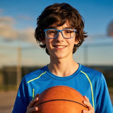 Boy holding a basketball on a basketball court with a clear sky